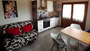 A compact living space with a kitchenette, a dining area, and a sofa with a polka dot pattern.