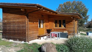 A wooden cabin with a porch, a table, and chairs.