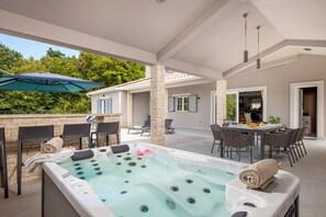 Relax in a spacious hot tub surrounded by comfortable seating and a dining area.