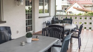 An outdoor patio with tables and chairs, a potted plant, and a decorative wall. - Vacation apartment I Waldstraße - ideal for up to 4 people (Alsbach-Hähnlein)