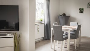 A modern dining area with a white table, grey chairs, and a grey floor lamp. - Vacation apartment I Waldstraße - ideal for up to 4 people (Alsbach-Hähnlein)