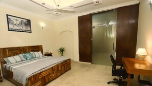 Une chambre à coucher avec un lit en bois, un bureau avec une chaise, un ventilateur de plafond et une porte coulissante.