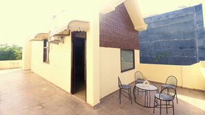Une terrasse sur le toit avec une petite table et des chaises, une fenêtre et une porte.