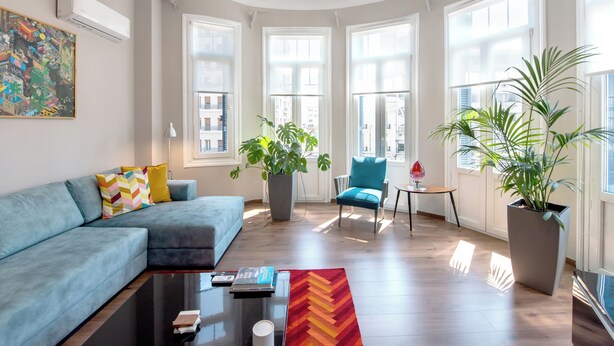 Uma sala de estar moderna com um sofá modular, uma mesa de centro e plantas em vasos.