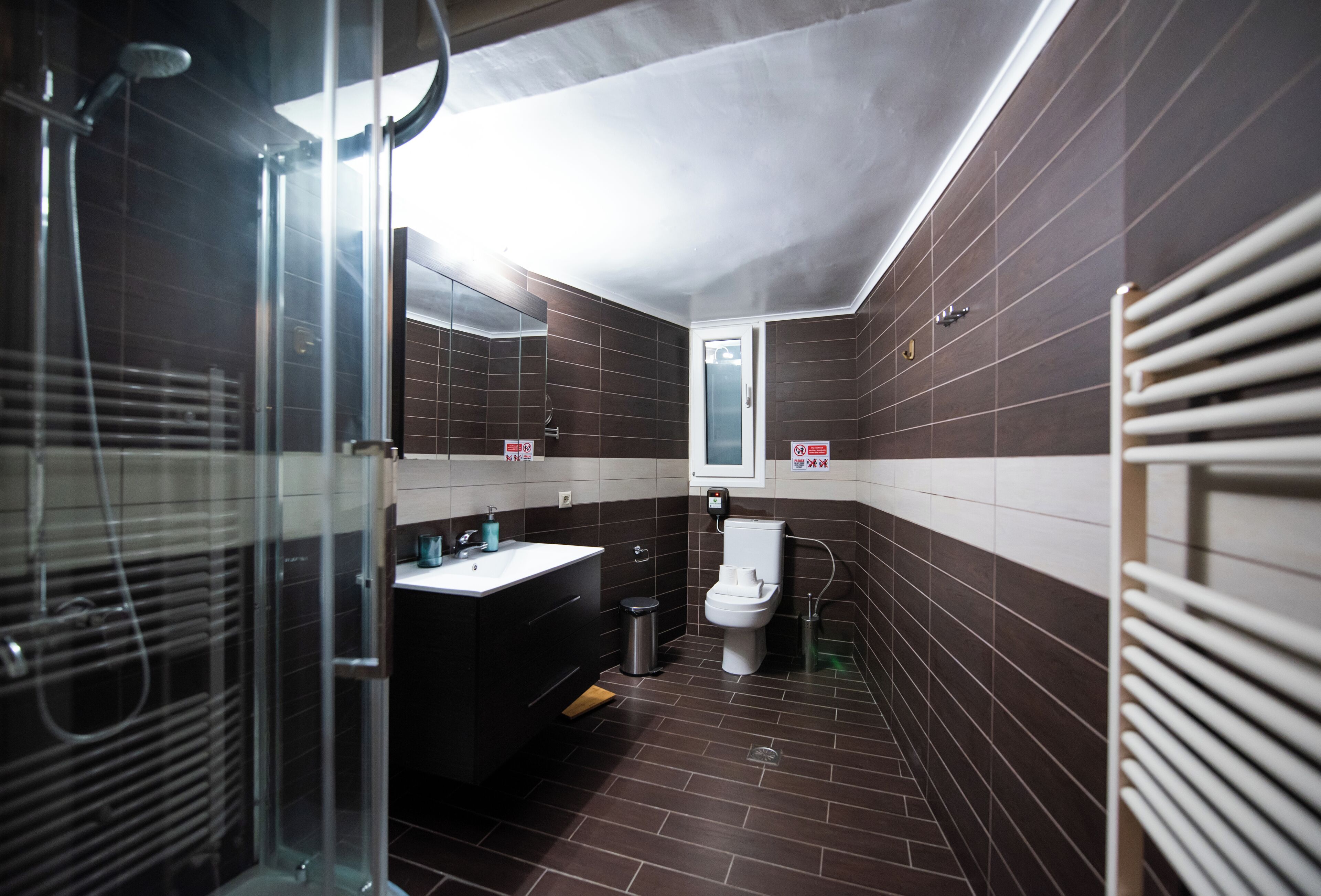 Une salle de bain moderne avec une douche à parois de verre, des toilettes blanches et un lavabo noir.