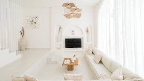 Een moderne woonkamer met een witte bank, een houten salontafel en een flatscreen televisie aan de muur.