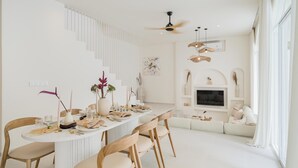 Een moderne eetruimte met een ronde tafel, houten stoelen en een plafondventilator.