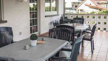 Eine Außenpatio mit Tischen, Stühlen, einem Blumentopf und einer Dekowand.