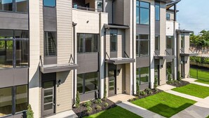 A modern multi-story residential building with large windows, balconies, and a well-maintained lawn. - Southside Chatt Condo - 2BR, Pet Friendly! (Chattanooga)