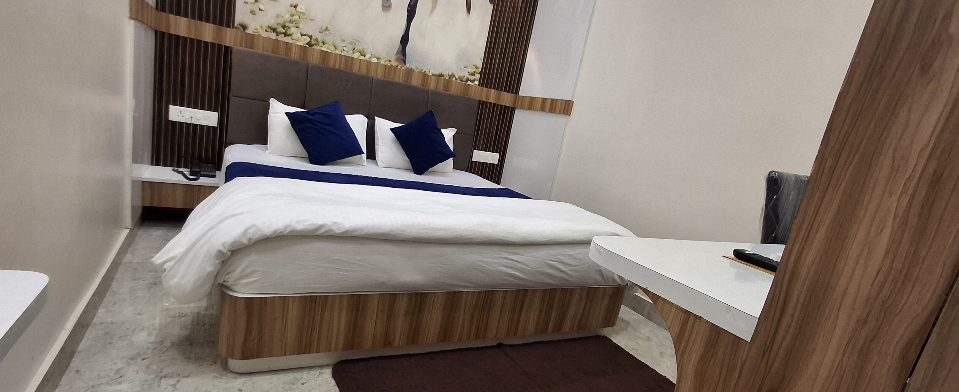 A modern bedroom with a wooden headboard, a white bedspread, and two blue pillows.