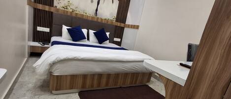 A modern bedroom with a wooden headboard, a white bedspread, and two blue pillows.