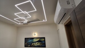 Eine Decke mit geometrischen Leuchten, einem Deckenventilator und einer Klimaanlage.