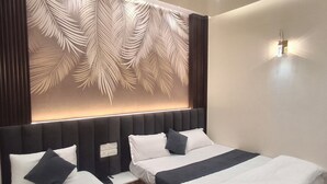 Ein Hotelzimmer mit einem großen Bett, einem Blattmuster-Kopfschild und einer Wandleuchte.