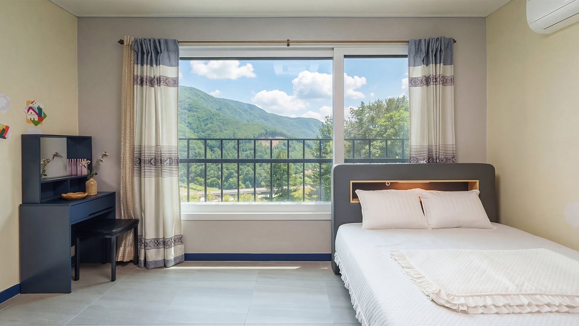 Un dormitorio con cama, escritorio y ventana con vistas a la montaña.