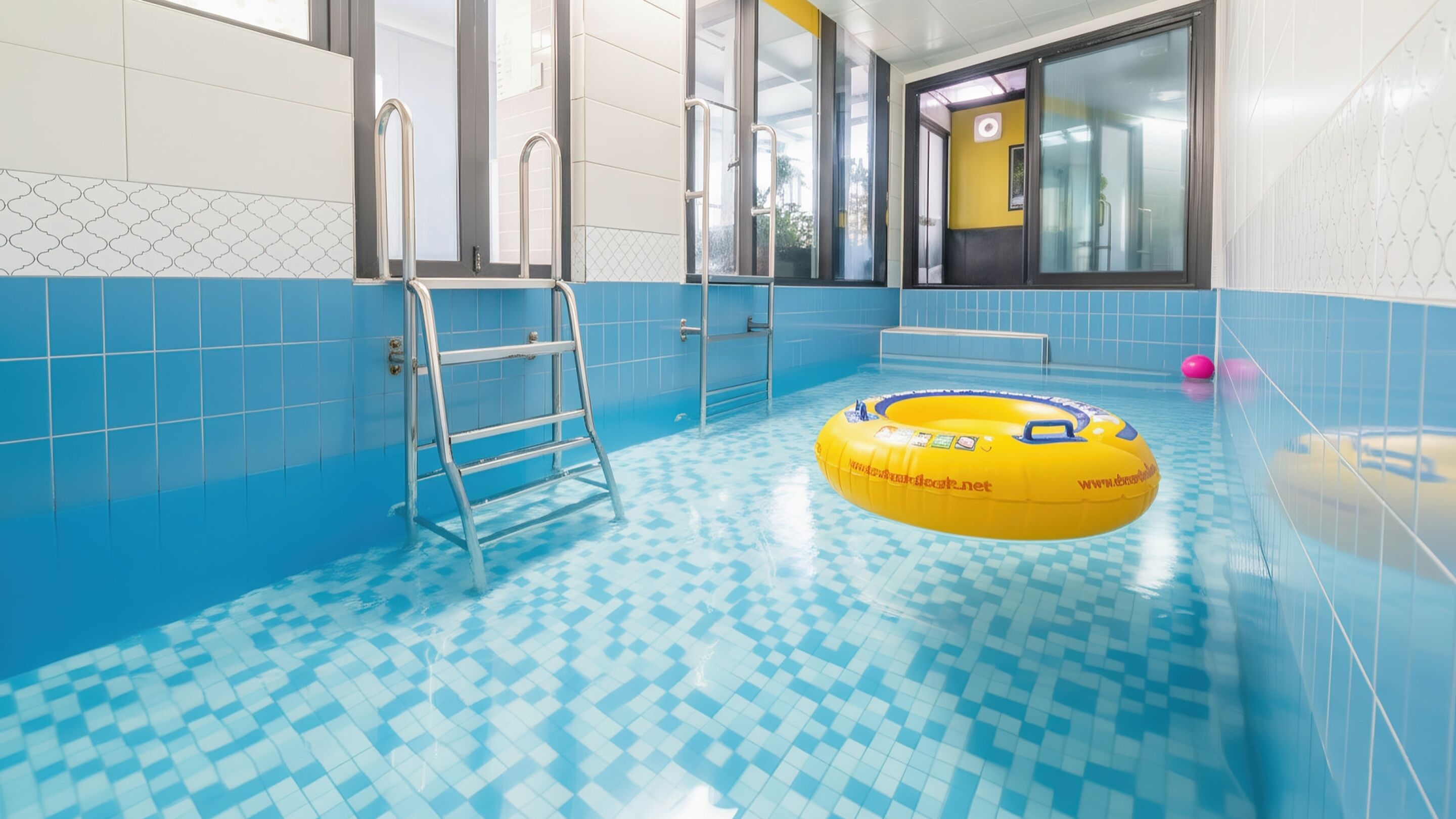 Ein Schwimmbecken mit einem Schachbrettmuster auf dem Boden, einer Leiter und einem gelben Schwimmreifen.