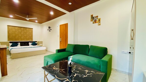 A modern living room with a green sofa, a black marble coffee table, and a bed with a wooden headboard. - Stay 10 Parallel Apartment Hotel (Indore)