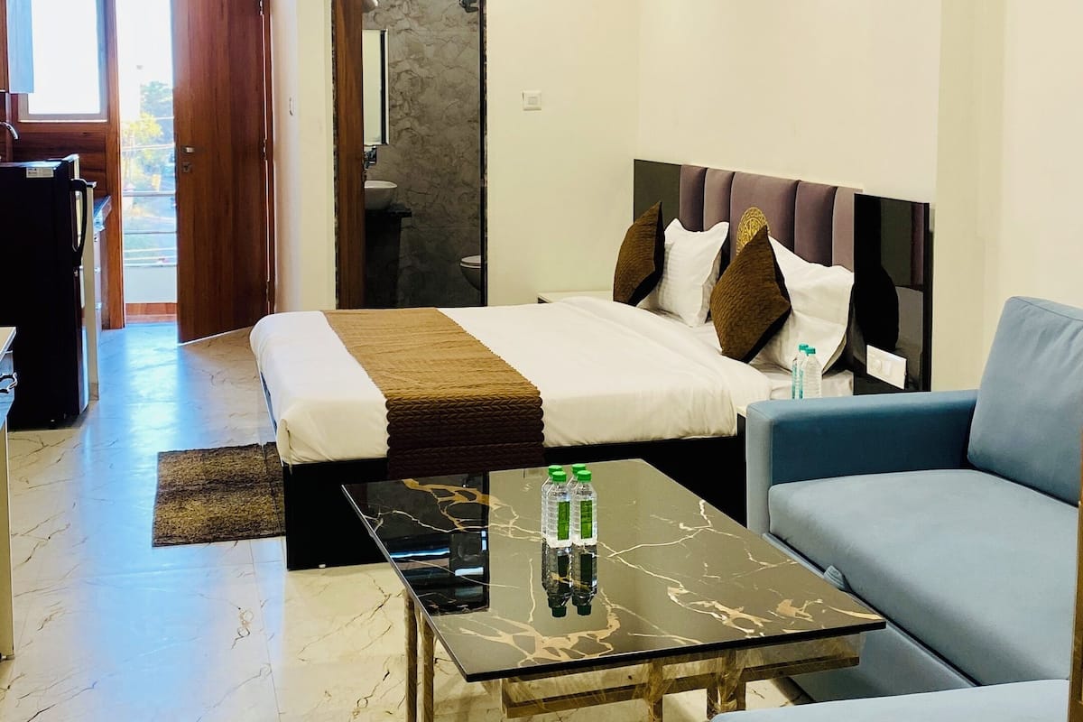 A modern hotel room with a bed, a sofa, a coffee table, and a ceiling fan.