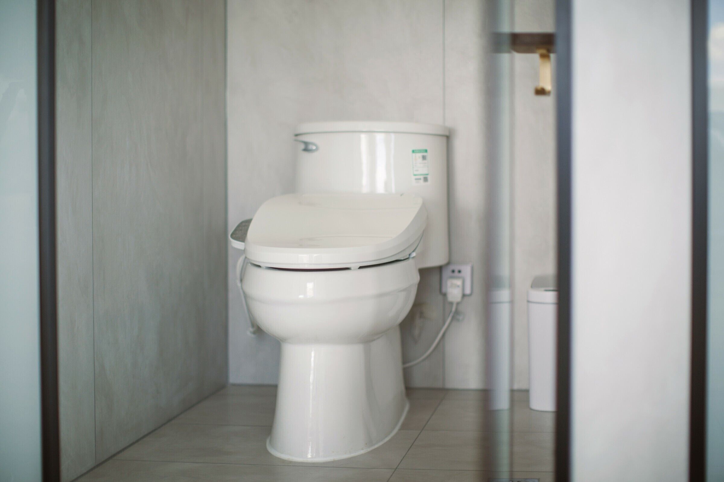 A white toilet in a bathroom with a tiled floor and a plain wall.