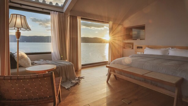 Un dormitorio con una cama grande, una mesita de noche, una silla, una lámpara y un televisor.