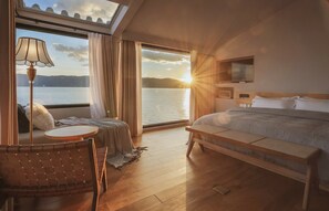 Une chambre à coucher avec un grand lit, une table de chevet, une chaise, une lampe et un téléviseur.