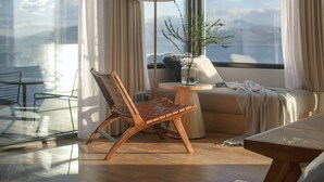 Una sala moderna con una silla de madera, una mesita redonda, una lámpara de pie y un sofá.
