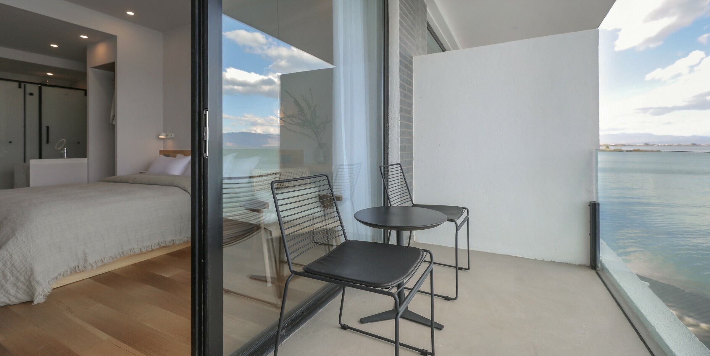 A balcony with a bed, a chair, and a table.