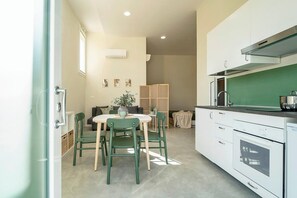 Una cocina compacta con armarios blancos, estufa y comedor con mesa y sillas.
