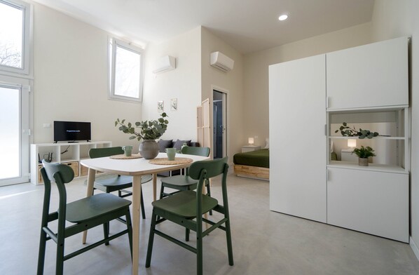 Una sala de estar moderna con comedor, televisor y un mueble blanco grande.
