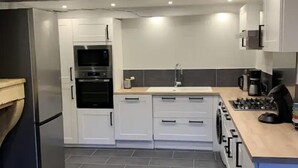 A modern kitchen with white cabinets, a built-in oven, a sink, and a stove. - Family country house for 11 people (Bulson)