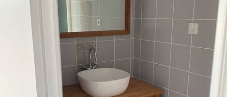 A bathroom with a white sink, wooden vanity, and a mirror.