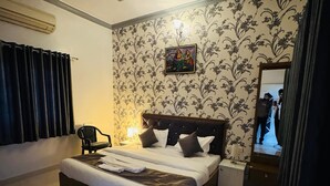 Une chambre bien rangée, avec un lit, une chaise, une table de chevet, un ventilateur de plafond et un climatiseur fixé au mur.