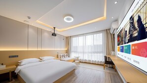 Una habitación de hotel moderna con una cama grande, mesitas de noche, un escritorio y un ventanal con cortinas.