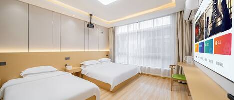 Habitación de hotel con dos camas, un escritorio, un proyector y un amplio ventanal con cortinas.