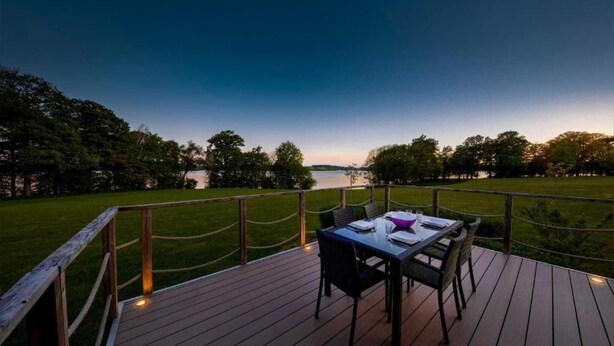 Une terrasse avec une table et des chaises donnant sur un plan d’eau.