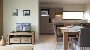 Une cuisine moderne avec des meubles en bois, un four à micro-ondes et un coin repas avec une table dressée pour deux personnes.