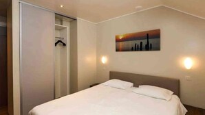 A hotel room with a bed, a wardrobe, and a painting on the wall. - Family Villa by the Lake (Boussu-lez-Walcourt)