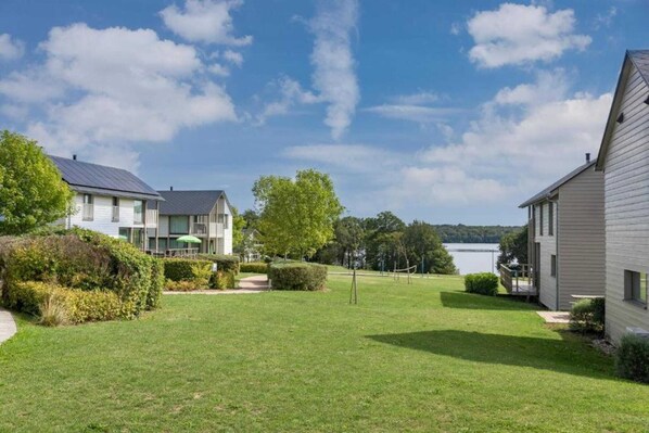 A residential area with houses, a lawn, and a lake in the background.