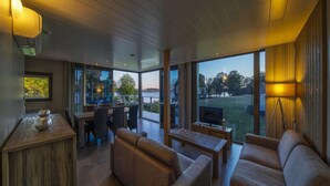 Ein modernes Wohnzimmer mit großem Fenster, einer Couch, einem Couchtisch und einem Essbereich mit Stühlen und Tisch.