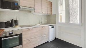 A modern kitchen with light wood cabinets, stainless steel appliances, and a dishwasher. - Modern apartment - 2BDR/6P - Paris 14e (Paris)