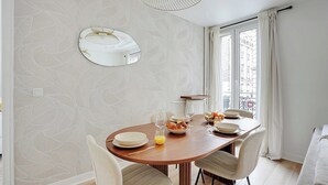A dining area with a round table, chairs, a bowl of fruit, and a glass of orange juice. - Modern apartment - 2BDR/6P - Paris 14e (Paris)