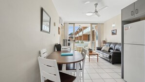 Eine moderne Küche mit Essbereich, Deckenventilator und Blick auf einen Balkon.