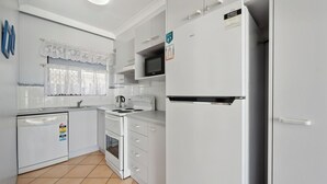 A modern kitchen with white cabinetry, a built-in microwave, a refrigerator, and a dishwasher.