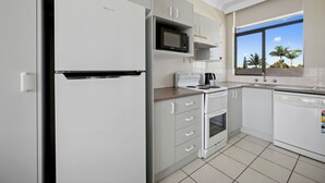 A modern kitchen with white cabinetry, a built-in microwave, a stove, and a dishwasher.