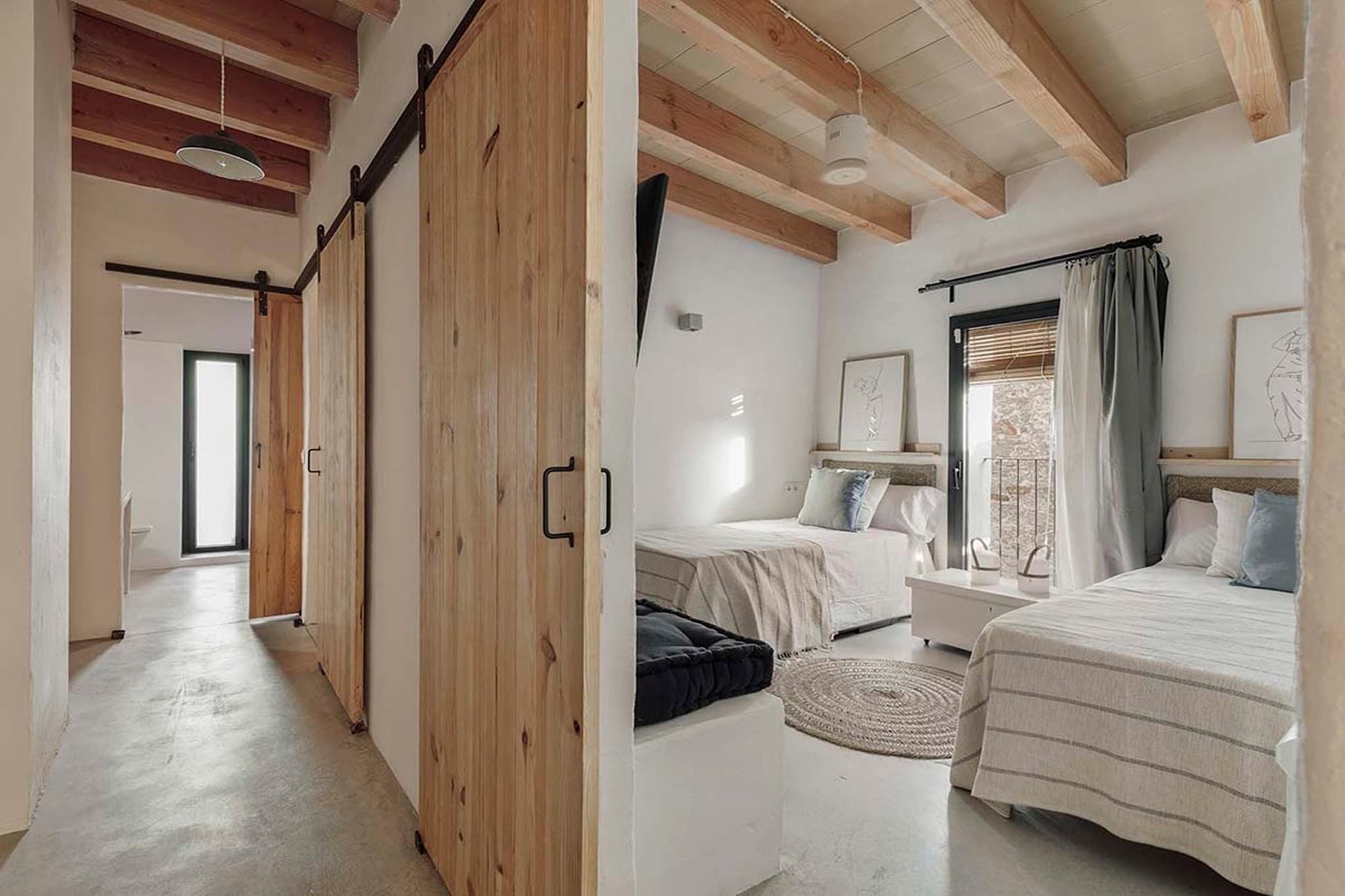 A modern bedroom with a large bed, two bedside tables, and a window with curtains.