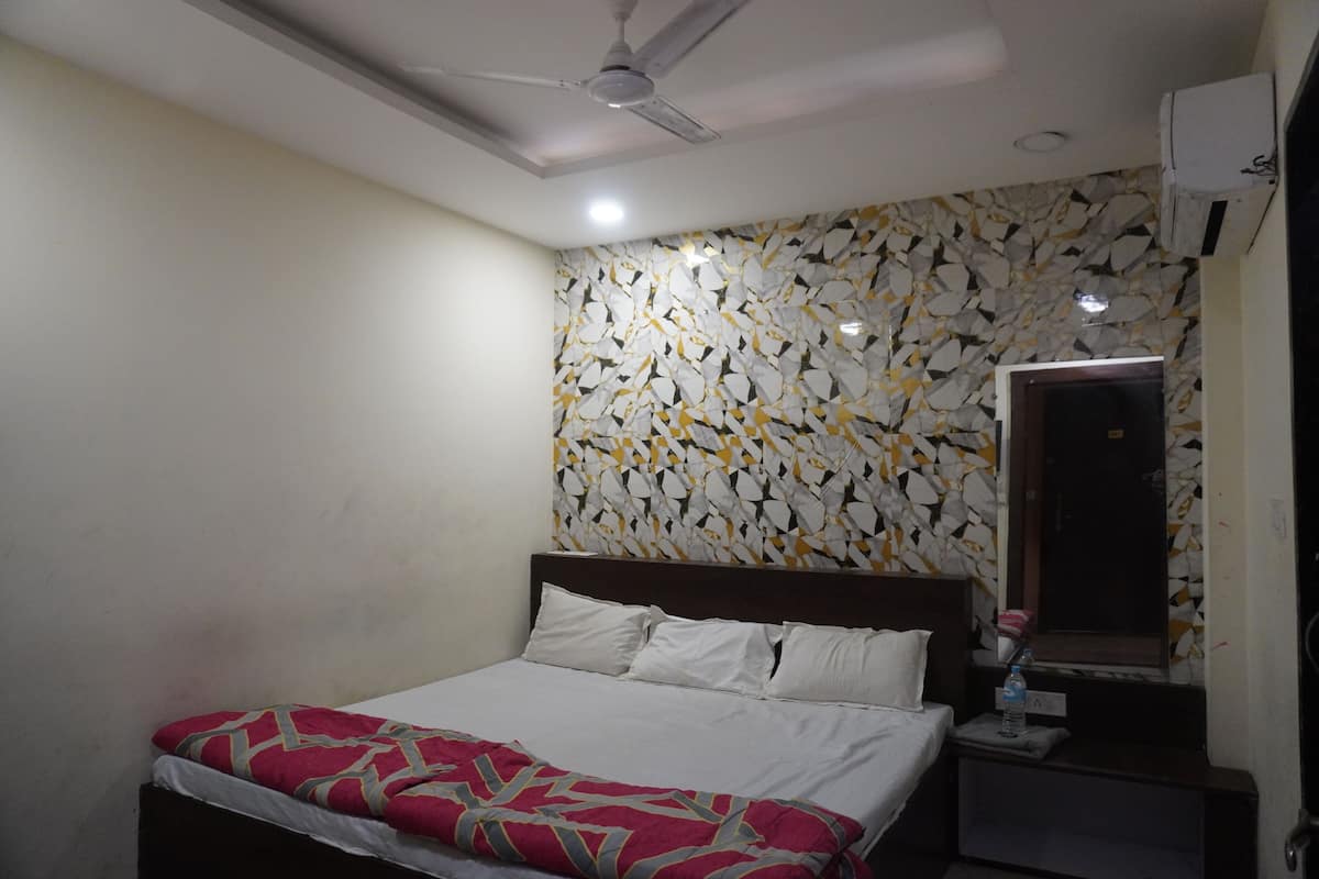 A hotel room with a bed, a nightstand, a ceiling fan, and a wall with a geometric pattern.