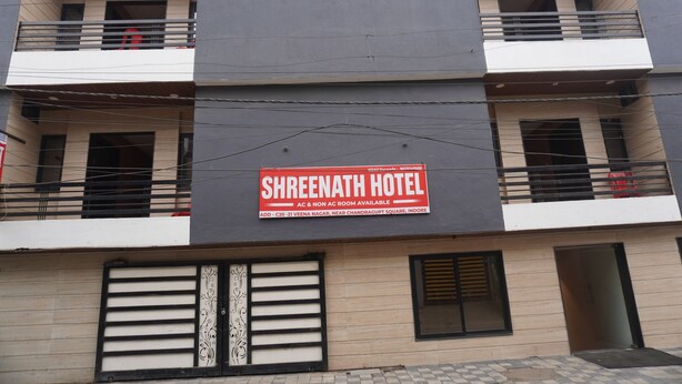 Un hotel con un letrero que indica 'Shreenath Hotel' y 'Habitaciones con aire acondicionado y sin aire acondicionado'.