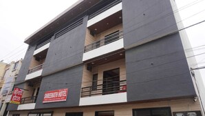 Un hotel de varios pisos con balcones en cada planta, un cartel anunciando el hotel y una entrada visible.
