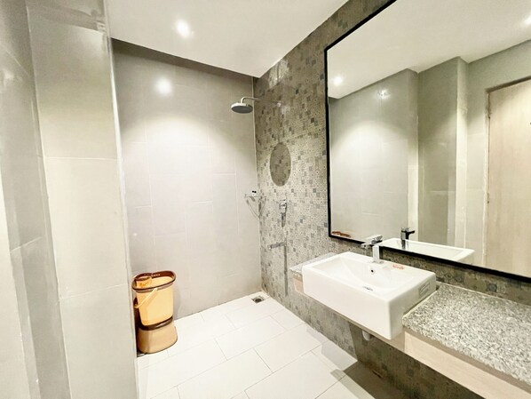 A modern bathroom with a large mirror, a white sink, and a shower area. - The Puri stays - Sea view & Temple (Puri)