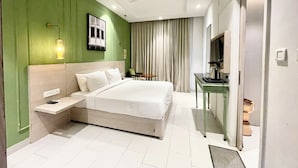 Een moderne hotelkamer met een groot bed, een bureau, een televisie en een plafondventilator.
