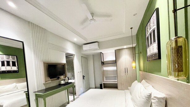 Een moderne hotelkamer met een bed, een bureau, een televisie en een spiegel.